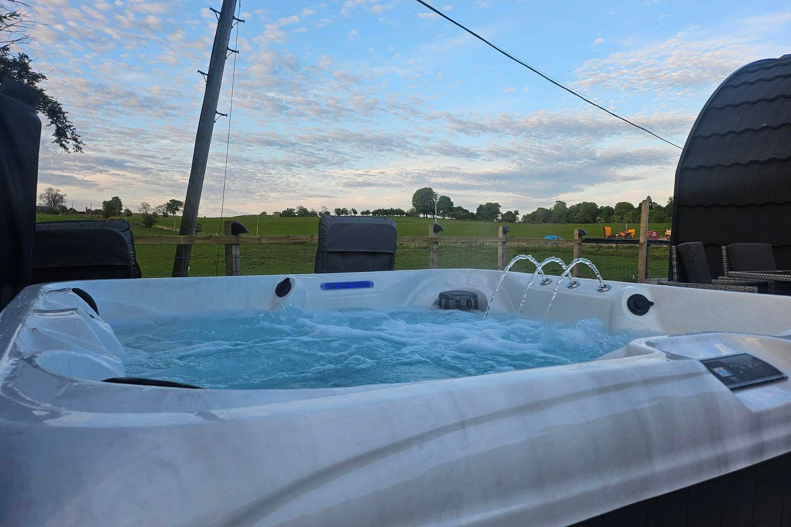 The hot tub, bubbling, with open farmland behind it