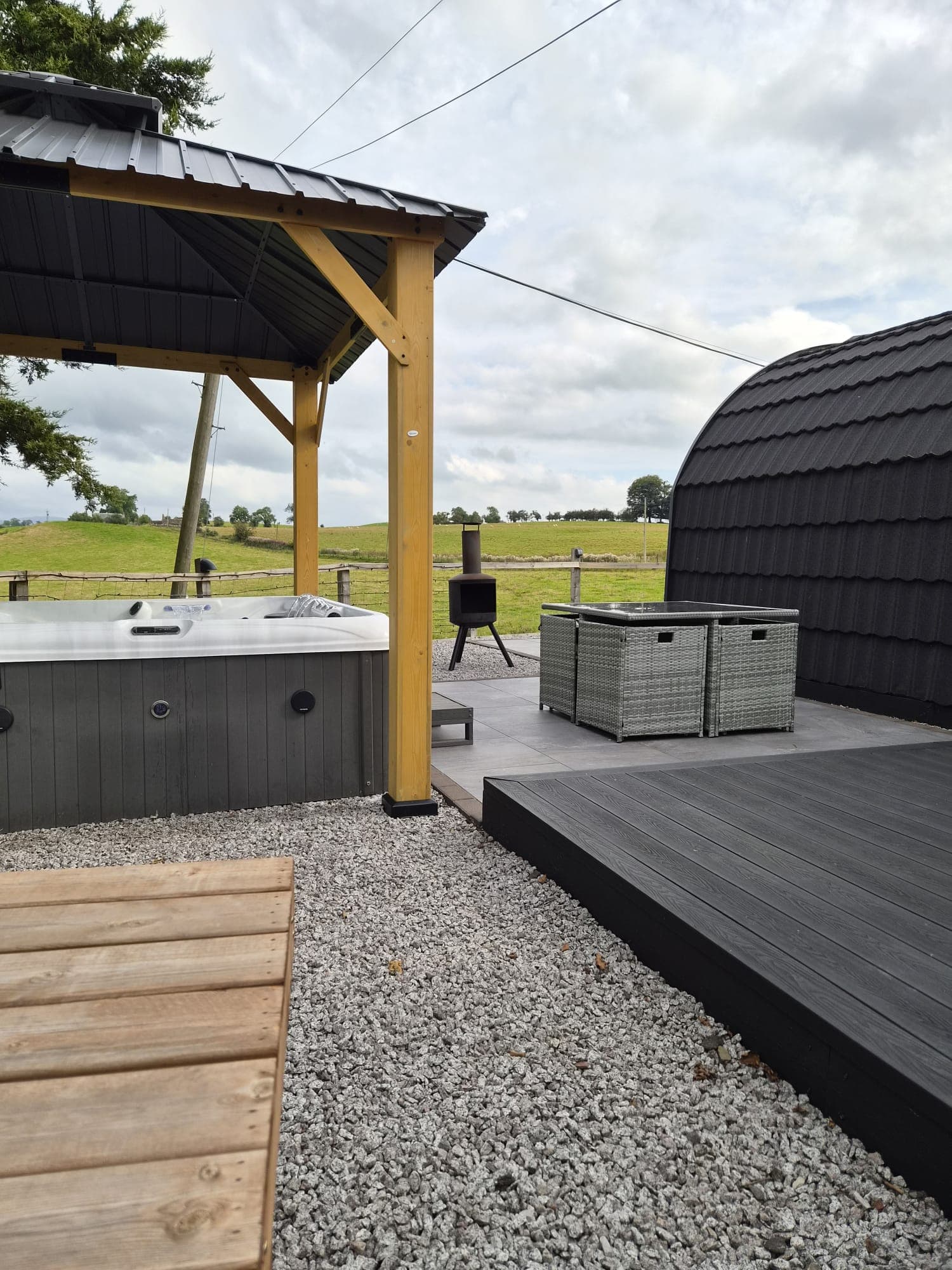 The Thistle Pod hot tub under its covered gazebo, farmland beyond